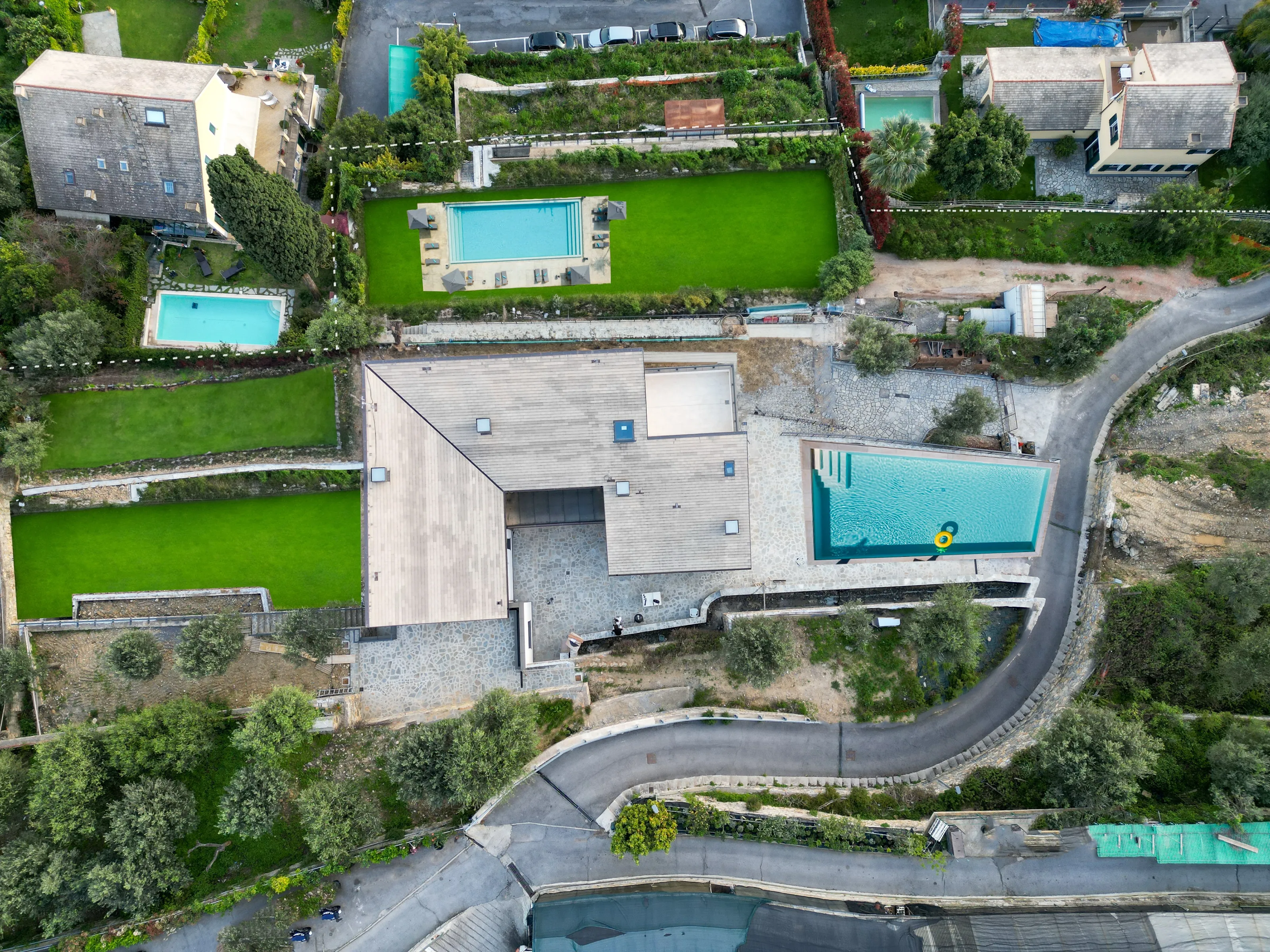 The same top-down view with green lawns on the terraces, a pool with loungers in the yard and a second pool beside the house