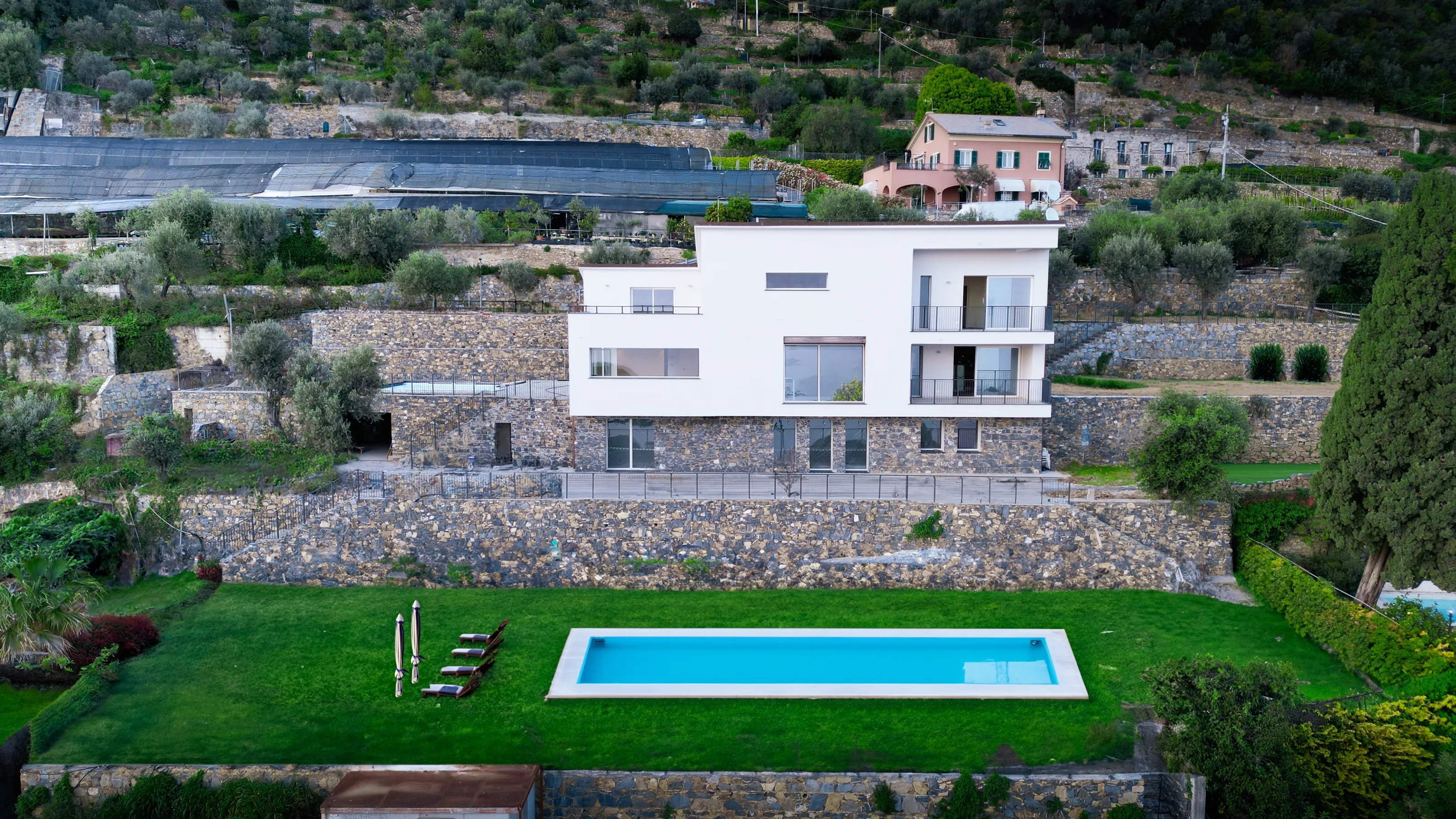 The same drone view with a lawn, a long pool and sun loungers in the yard, and the building site cleared
