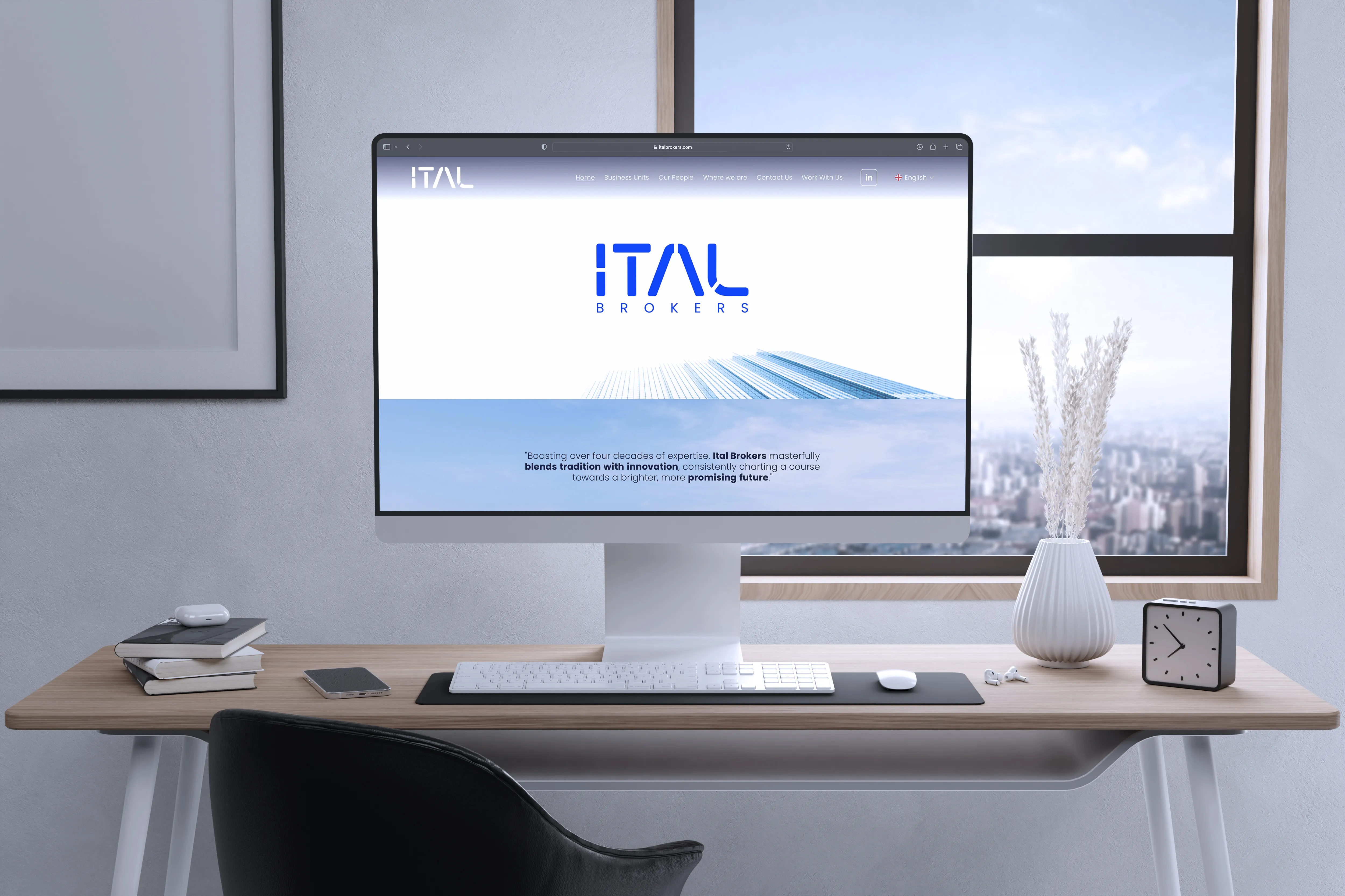 Mockup of the ITAL Brokers homepage on a desktop screen, on a wooden desk by a window