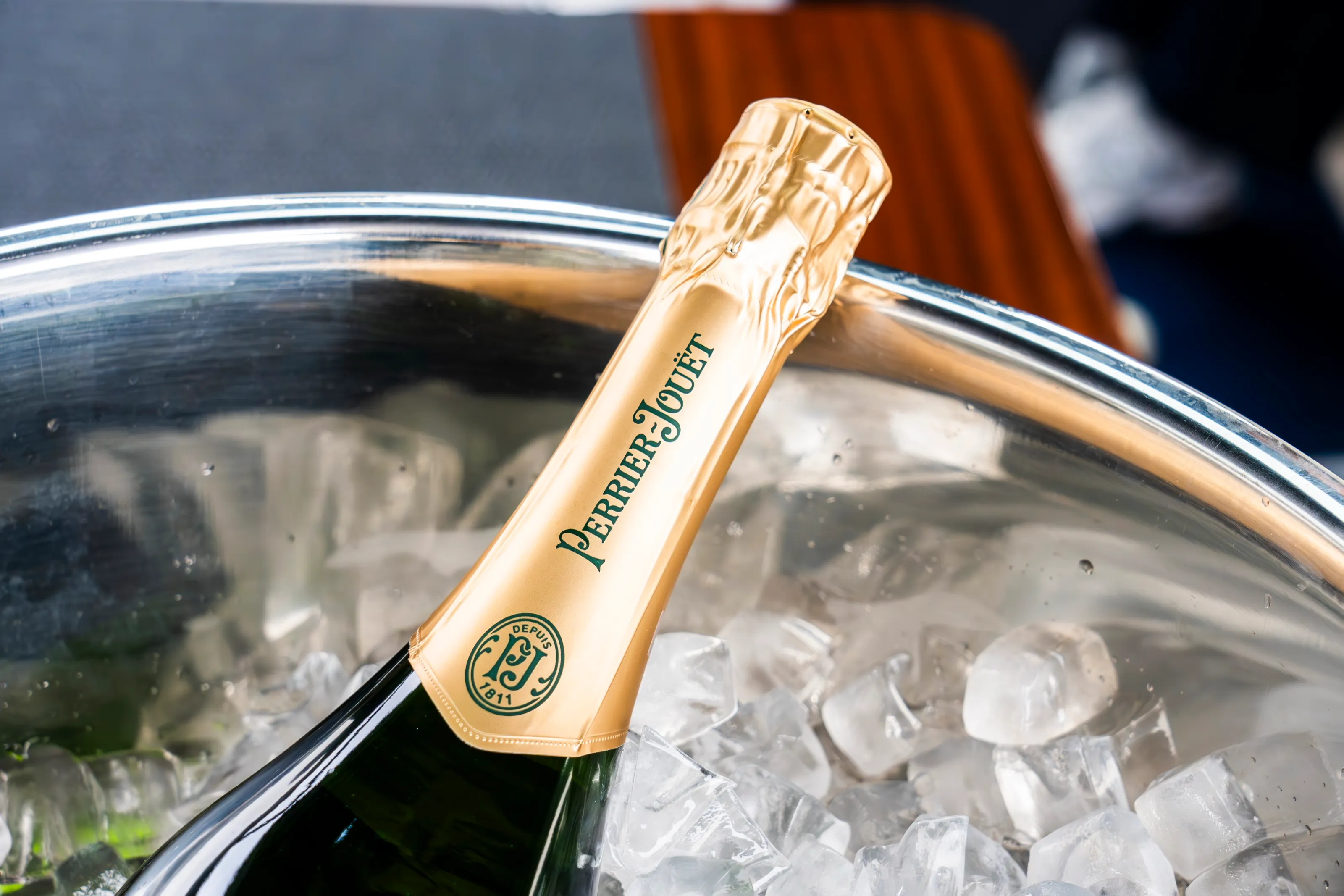The gold foil neck of a champagne bottle in an ice bucket