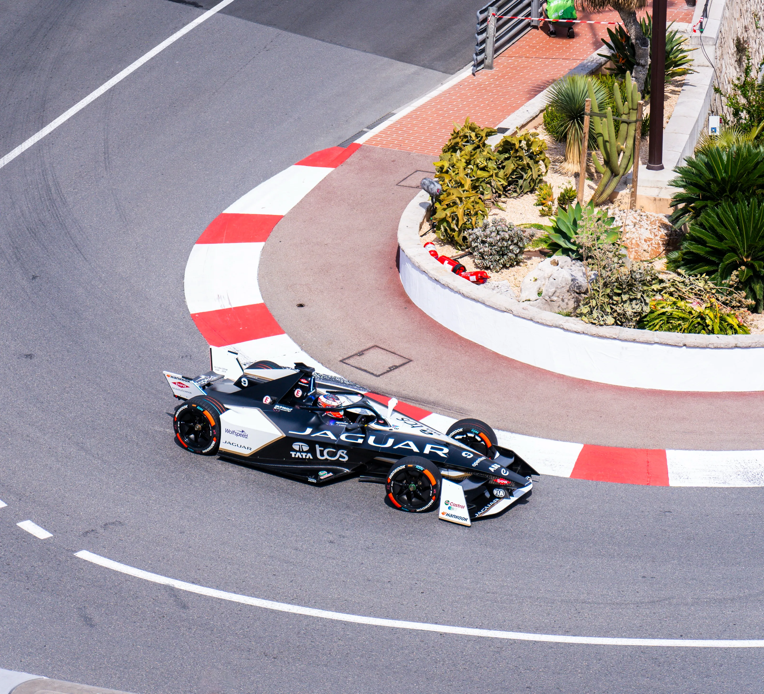 A Jaguar Formula E car takes the hairpin of the Monaco circuit, seen from above