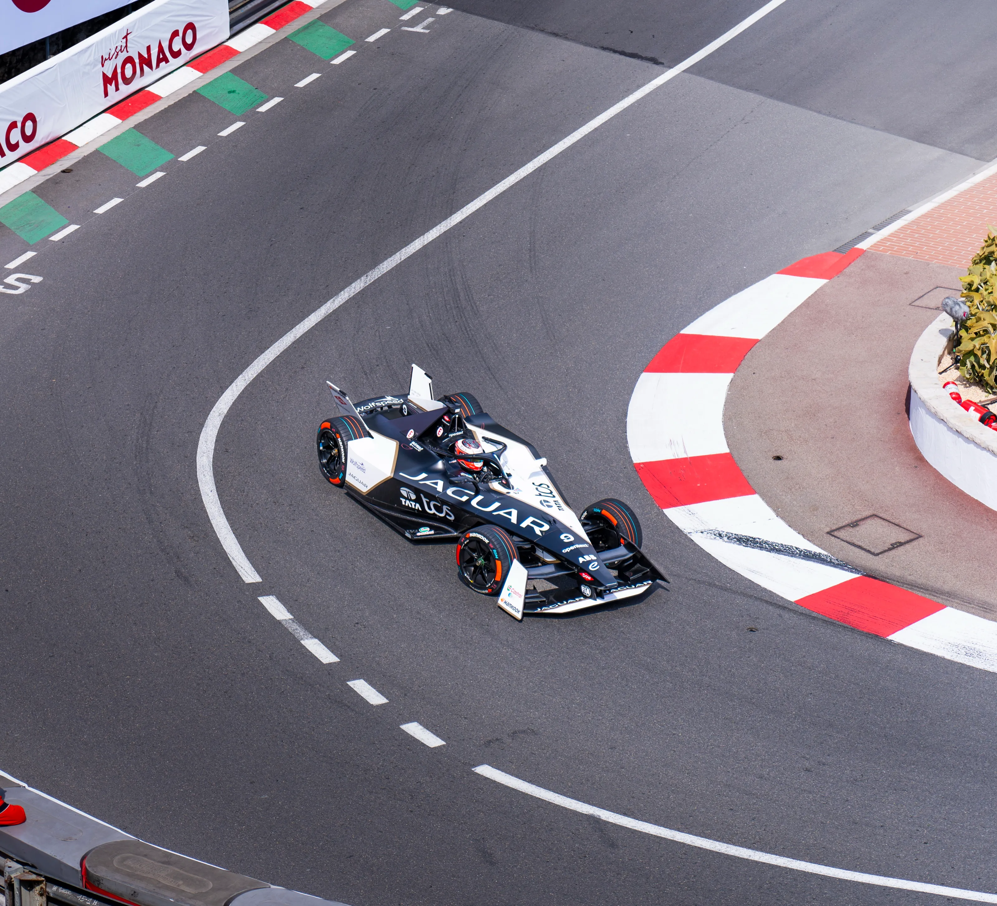 The Jaguar Formula E car entering the Monaco hairpin, seen from above, still away from the red and white kerb
