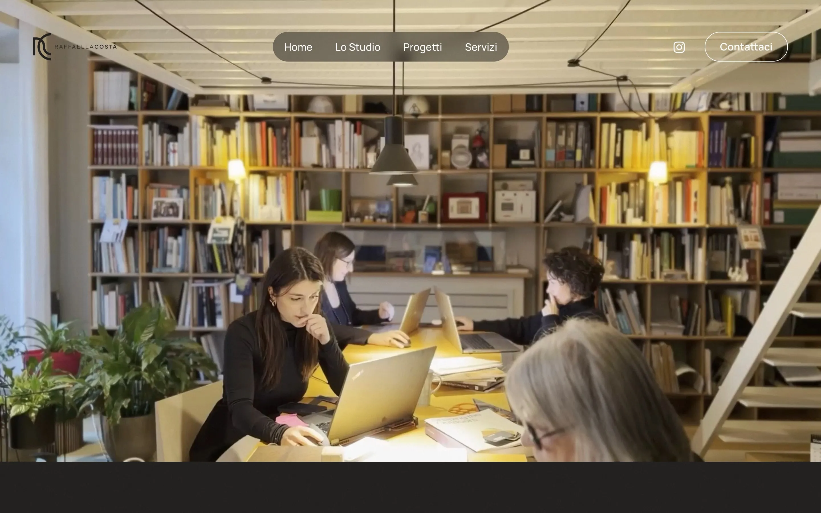 Screenshot of the raffaellacosta.com homepage: the logo, a rounded menu with Home, Lo Studio, Progetti and Servizi, and a Contattaci button, over a frame of the header film in which four women work around a long yellow table with laptops, in front of bookshelves that reach the ceiling