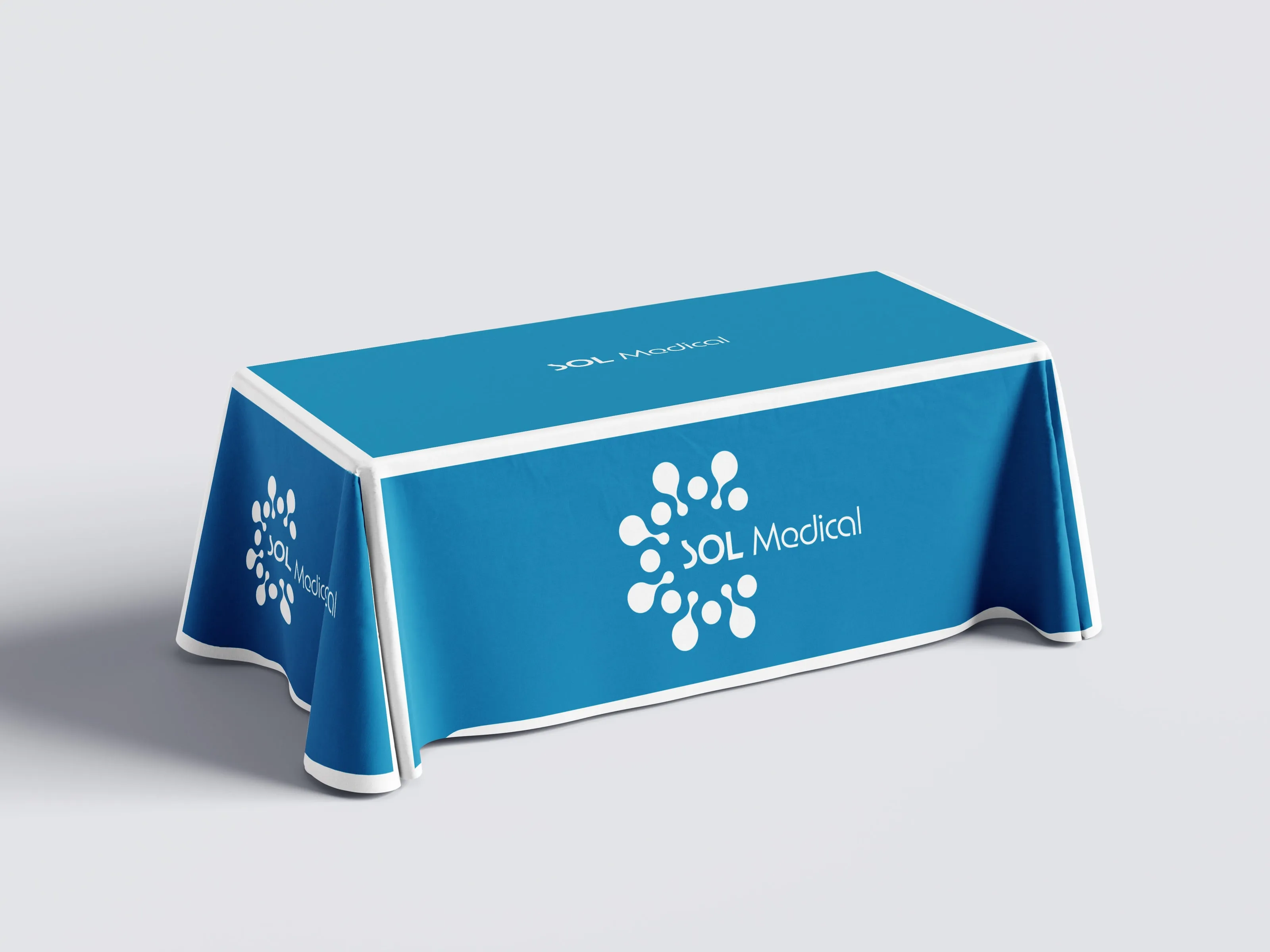 Mockup of a cerulean tablecloth with a white border over a rectangular table: the full logo in white on the front and on the side, and the name alone on the top