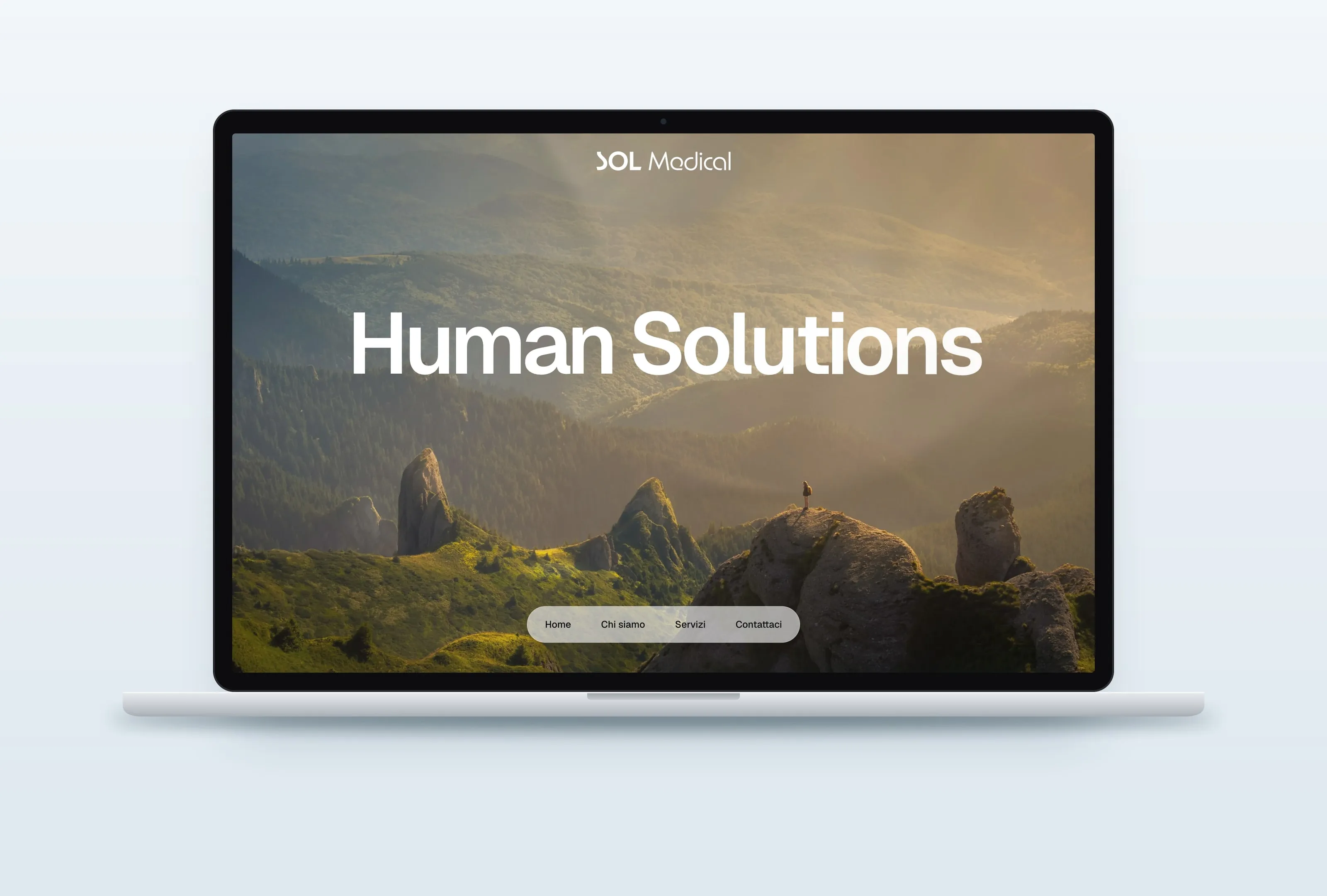 Mockup of a laptop showing the solmedical.group homepage: the name SOL Medical in white at the top, Human Solutions in large white letters over forested mountains and rock pinnacles in golden light, a tiny figure standing on a rock, and the white menu pill with Home, Chi siamo, Servizi and Contattaci at the bottom