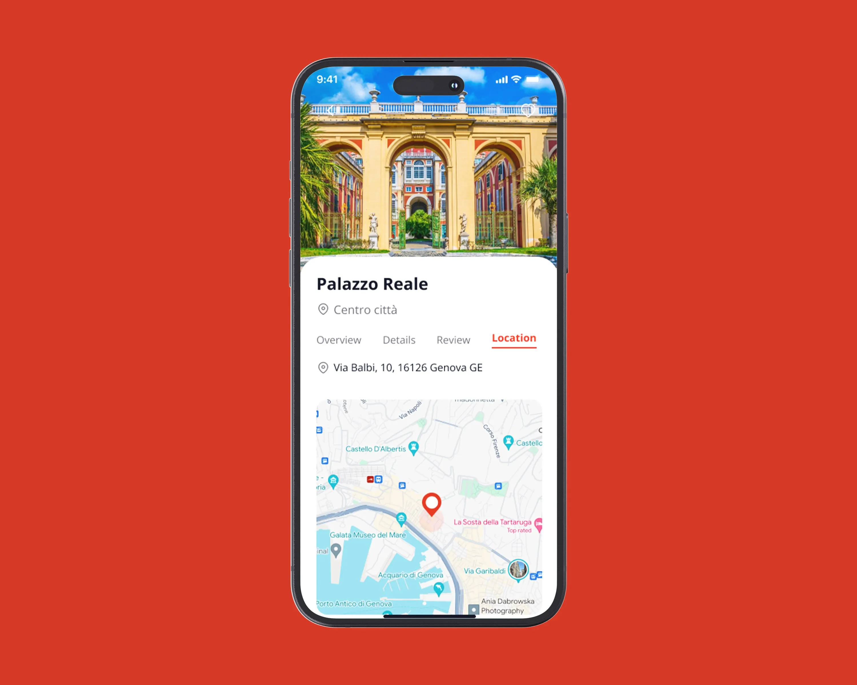 Mockup of a phone showing the Visit Genova app on the Palazzo Reale page, with a photo of the palace courtyard and a map, on a red background